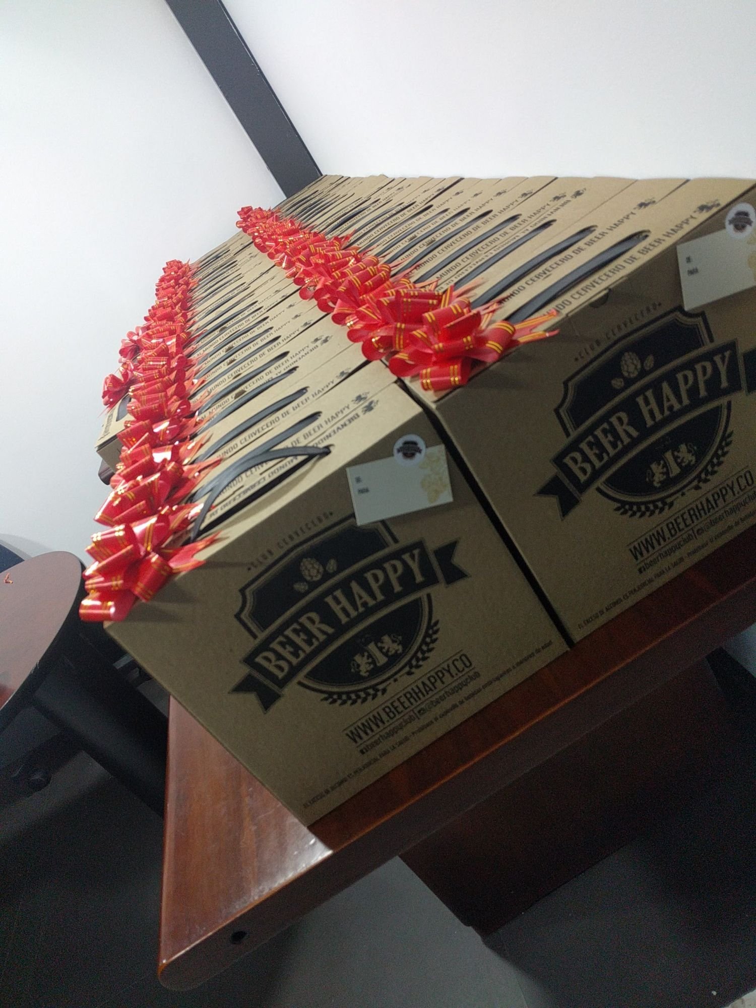 A table full of Beer Happy Club boxes tied with red ribbons, ready to ship