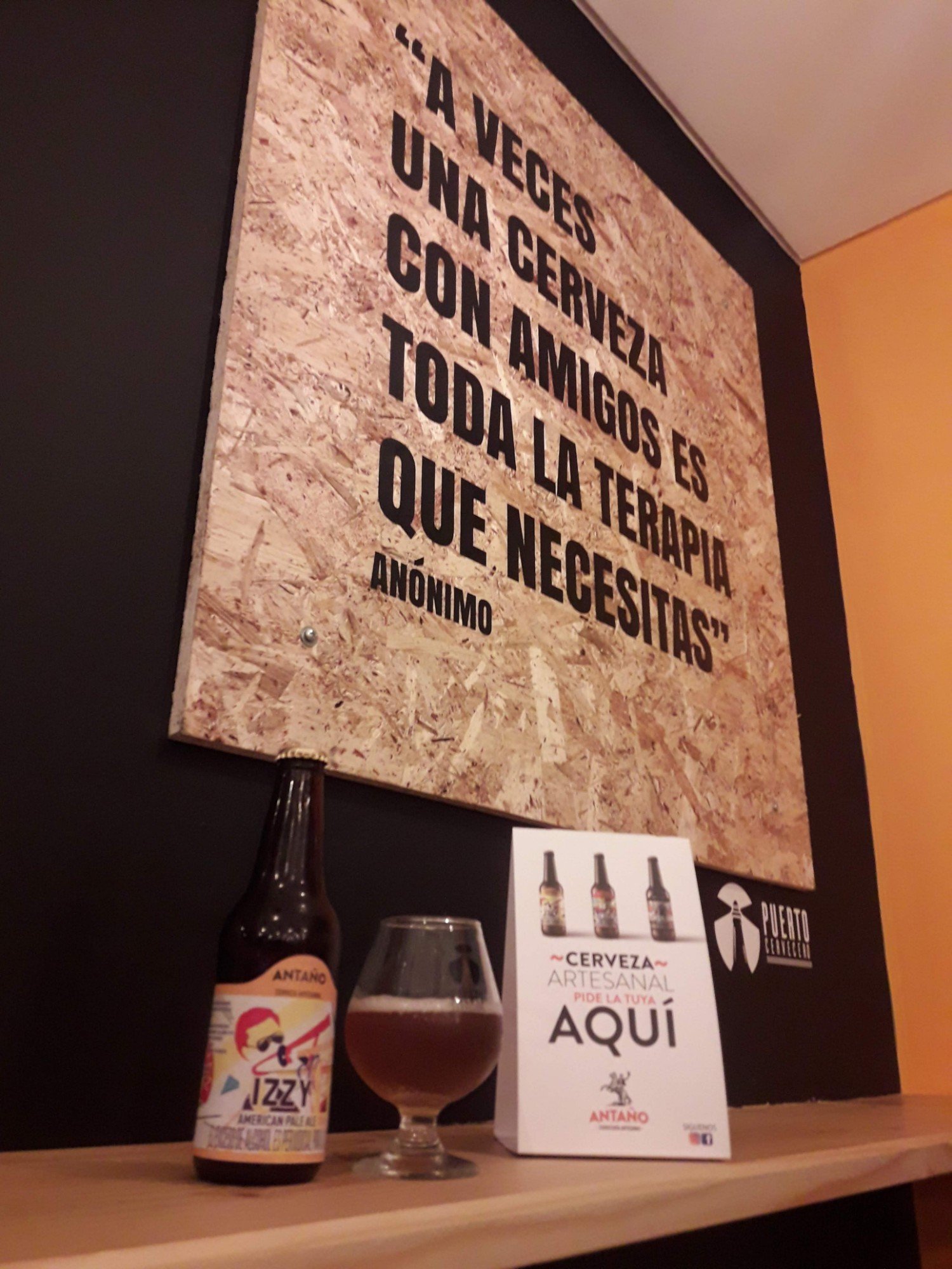 An Antaño craft beer under a wall quote at Puerto Cervecero
